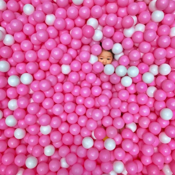 toddler on pink and white ballpit